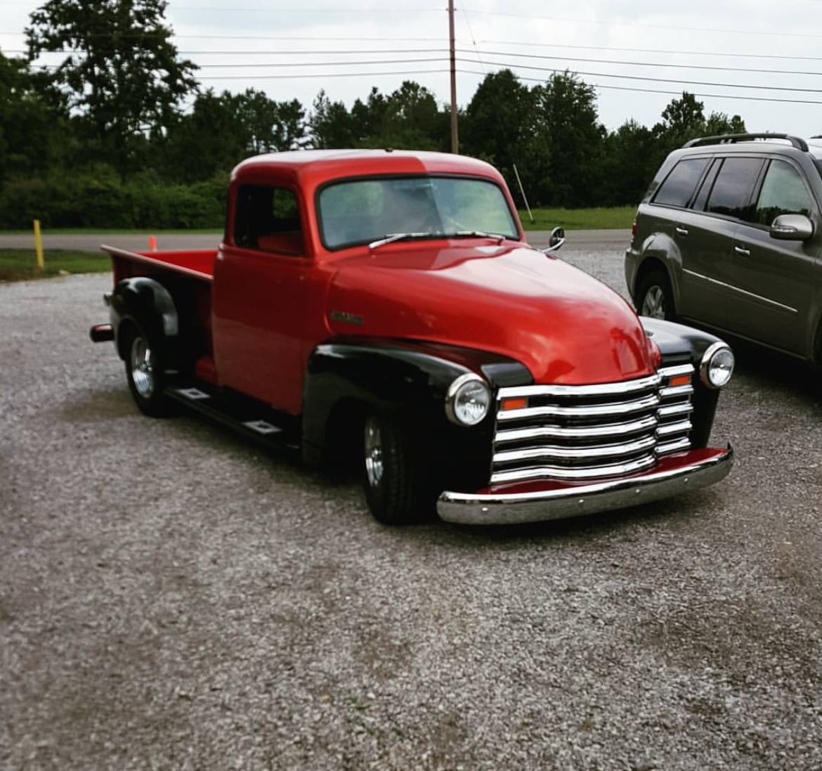 Classic truck sitting in a parking lot, the truck is red and black