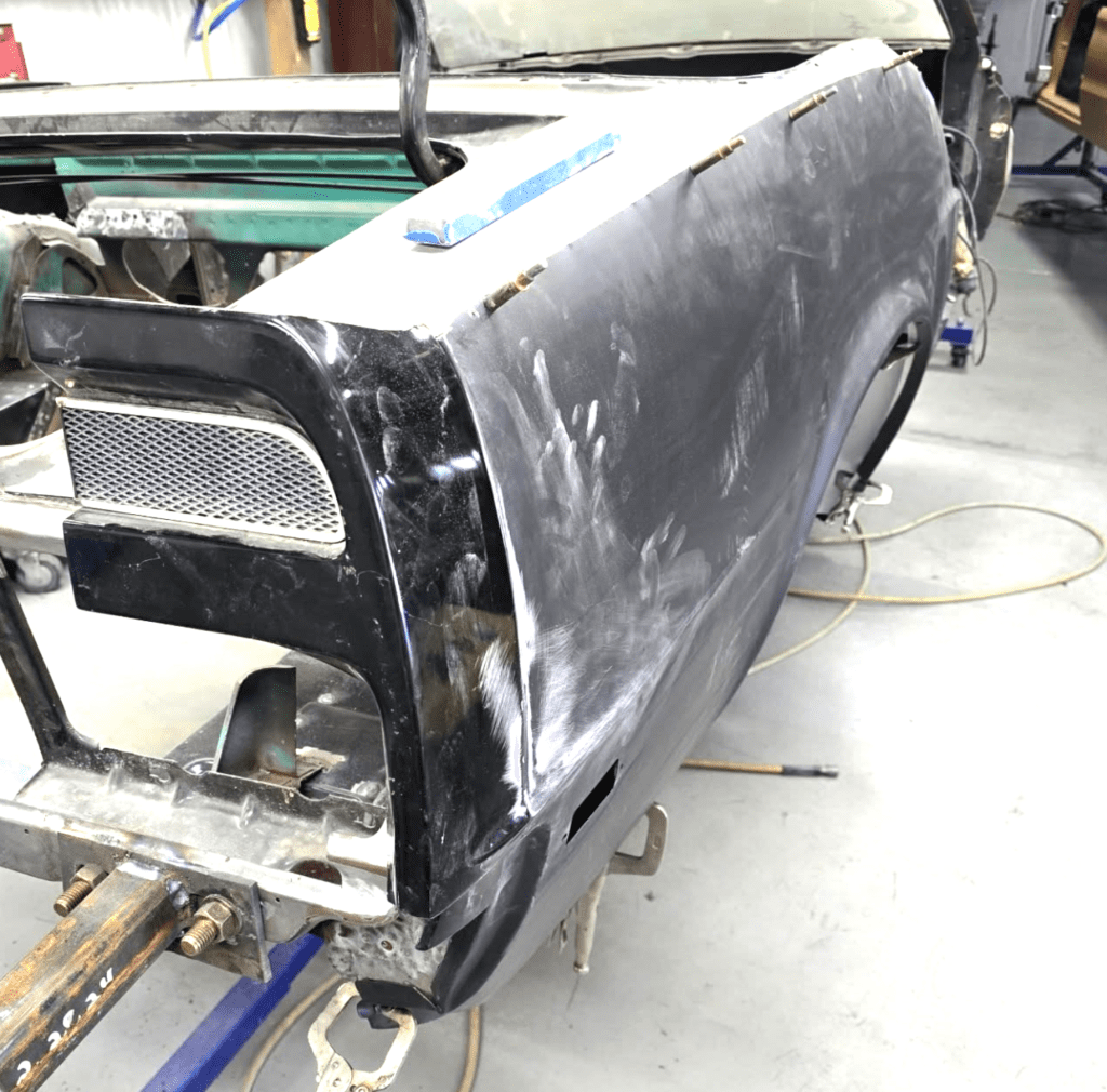 Car taken apart in restoration process, showing dusty hand prints