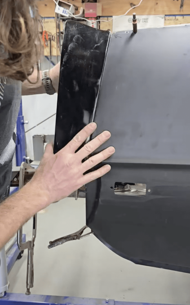 Cecil Henry placing parts on the rear end of a black car that has not been painted yet